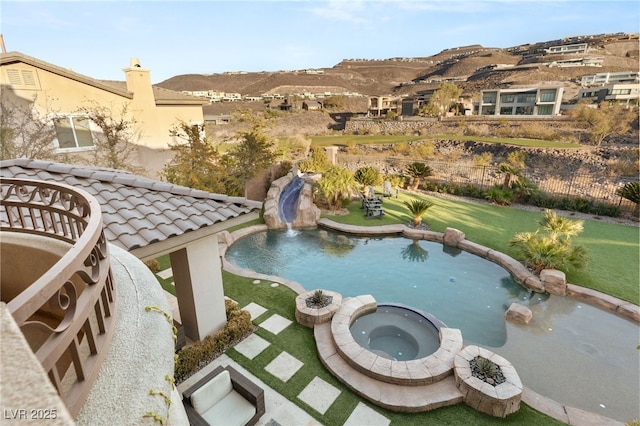 view of swimming pool with a mountain view, a lawn, an in ground hot tub, and a water slide