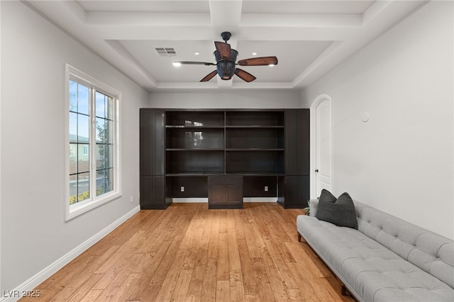 unfurnished office featuring a raised ceiling, ceiling fan, and light wood-type flooring