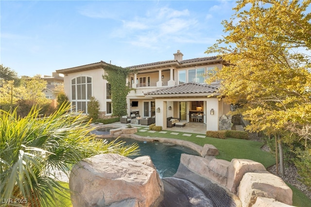 back of house with a patio area, outdoor lounge area, a balcony, and a lawn