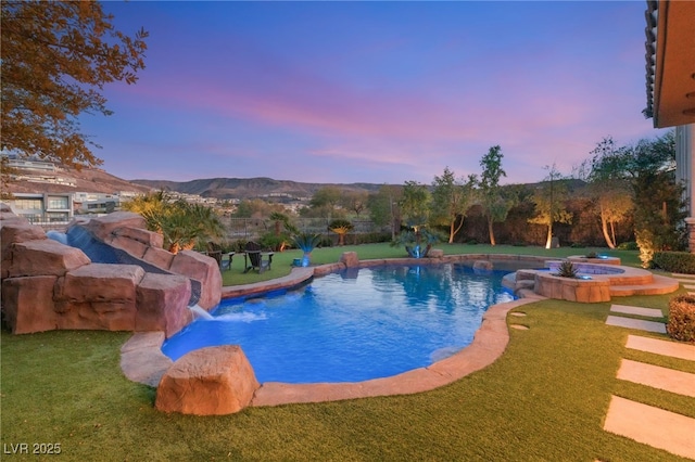 pool at dusk with a mountain view and a lawn