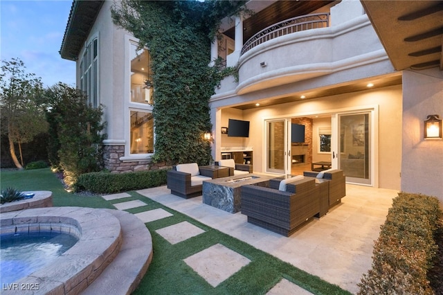 view of patio with a balcony and an outdoor living space with a fire pit