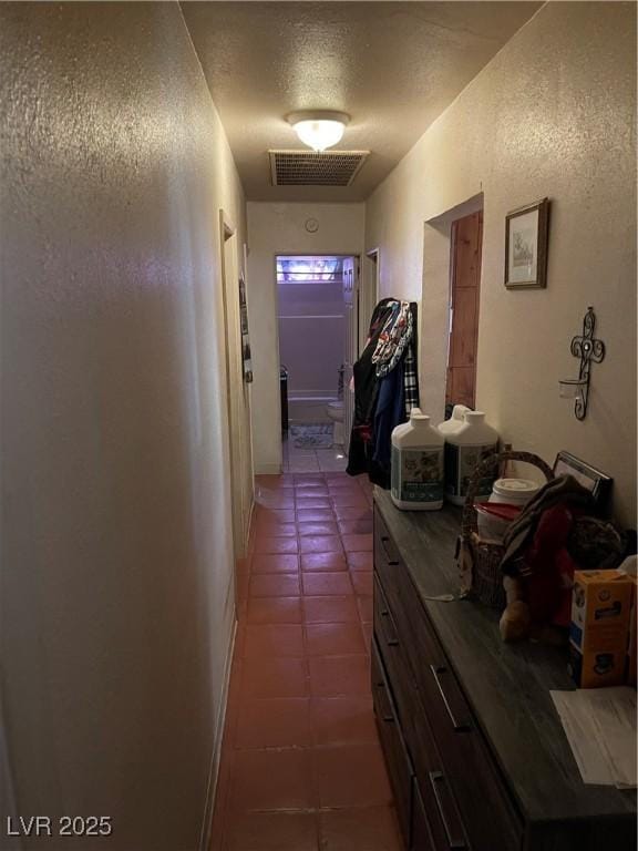 hallway featuring dark tile patterned floors and a textured ceiling