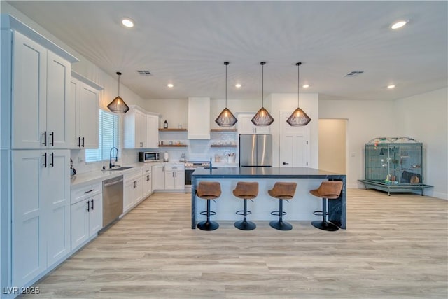 kitchen with sink, appliances with stainless steel finishes, a kitchen breakfast bar, white cabinets, and a kitchen island