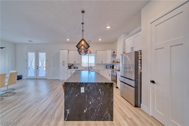 kitchen featuring appliances with stainless steel finishes, white cabinetry, hanging light fixtures, a center island, and french doors