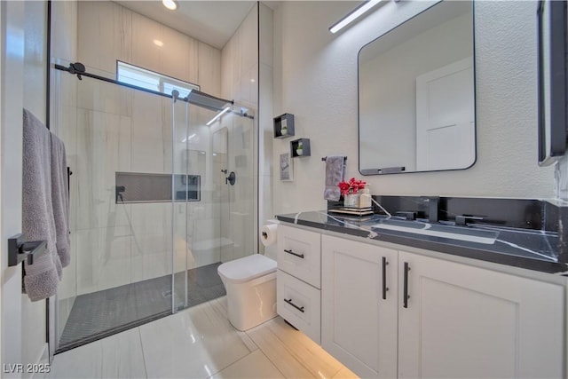 bathroom with vanity, a shower with shower door, and toilet