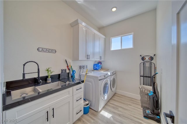 clothes washing area with cabinets, independent washer and dryer, sink, and light wood-type flooring