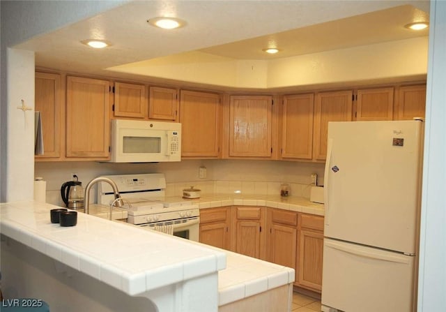 kitchen with light tile patterned floors, tile countertops, white appliances, and kitchen peninsula