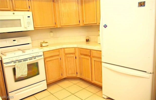 kitchen featuring white appliances, tile counters, and light tile patterned floors