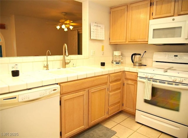 kitchen featuring white appliances, tile counters, sink, and light tile patterned floors