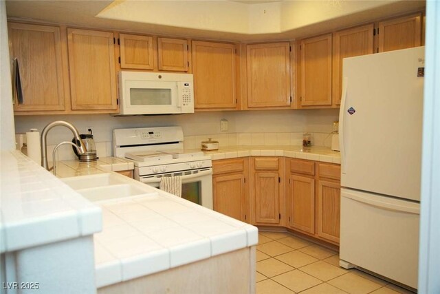 kitchen featuring white appliances, tile counters, light tile patterned flooring, and a sink