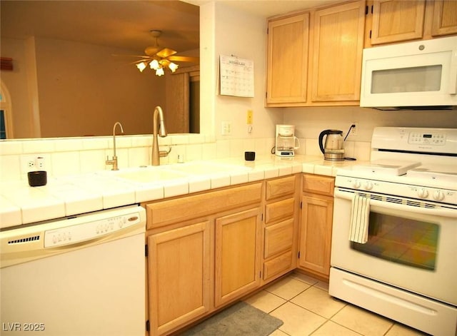 kitchen featuring a sink, white appliances, tile countertops, and light tile patterned floors