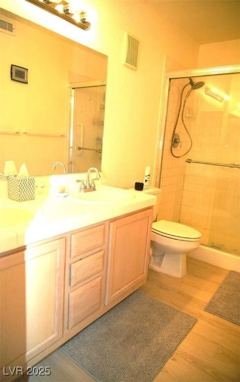 bathroom with visible vents, wood finished floors, and a shower stall