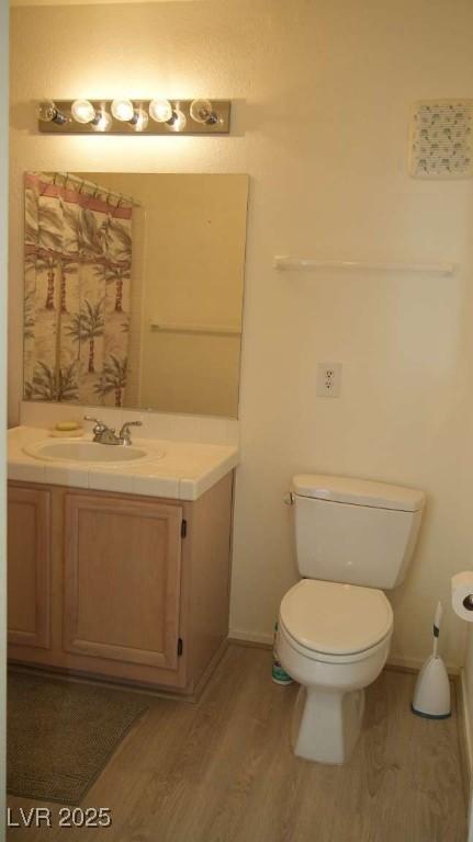 full bath featuring a shower with shower curtain, toilet, wood finished floors, and vanity