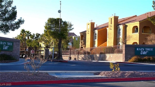 view of street with curbs, a gated entry, and street lighting