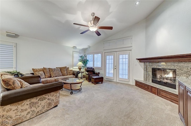 living room featuring french doors, high vaulted ceiling, light carpet, ceiling fan, and a high end fireplace