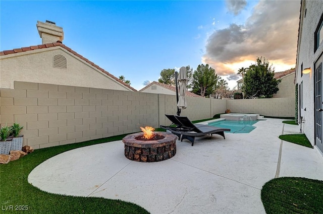 patio terrace at dusk with a fenced in pool and a fire pit