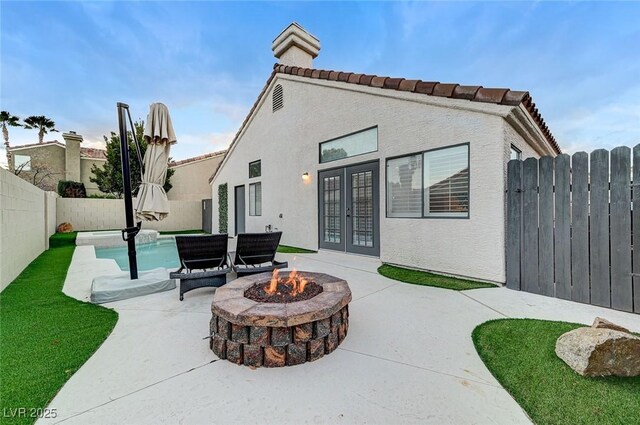 rear view of house with a patio, an outdoor fire pit, and french doors