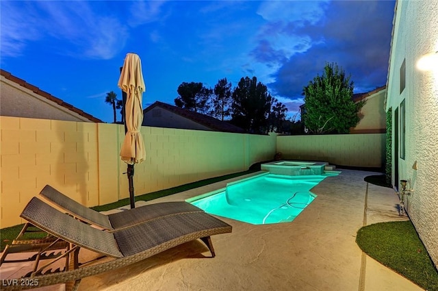 pool at dusk with a patio and an in ground hot tub