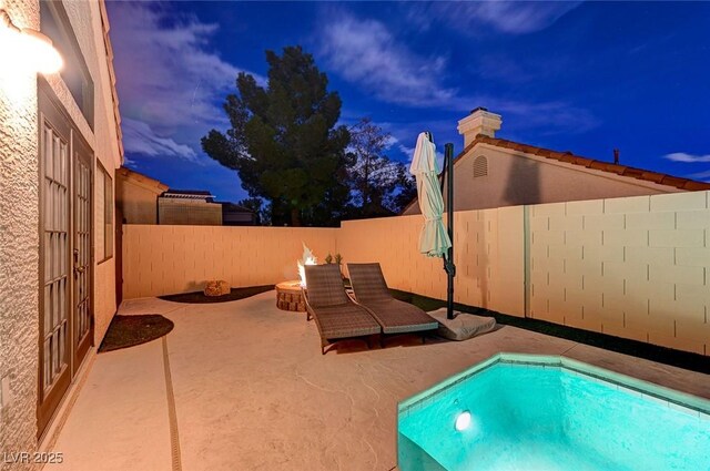 pool at dusk featuring a fire pit and a patio