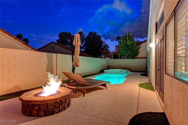 pool at dusk featuring a patio area and an outdoor fire pit