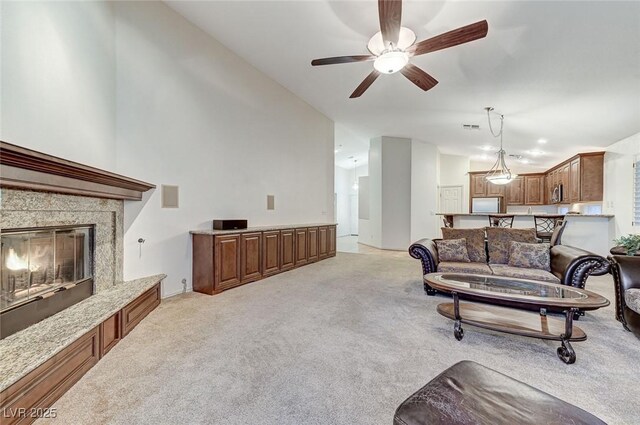 living room with a fireplace, light colored carpet, ceiling fan, and vaulted ceiling