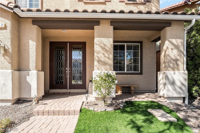 view of exterior entry with stucco siding and a tiled roof