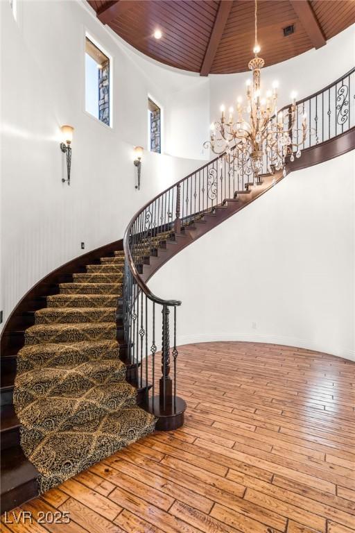 stairway with wood-type flooring, wooden ceiling, and beam ceiling