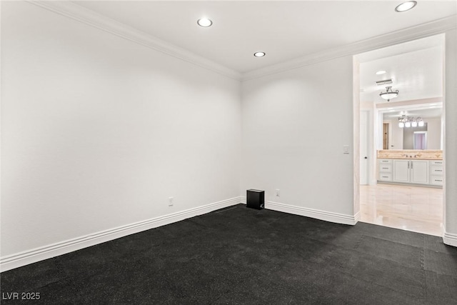 empty room featuring dark colored carpet, crown molding, and sink