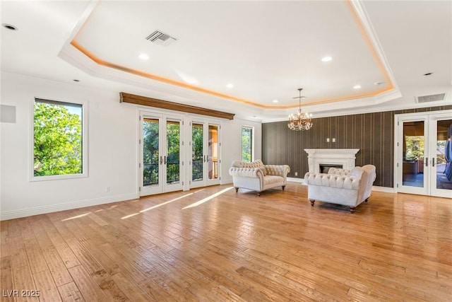 unfurnished room featuring crown molding, a tray ceiling, light hardwood / wood-style floors, and french doors