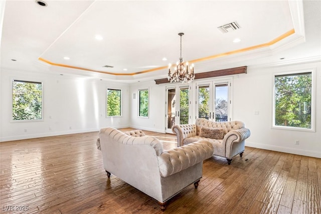 living room featuring a raised ceiling, ornamental molding, and hardwood / wood-style floors