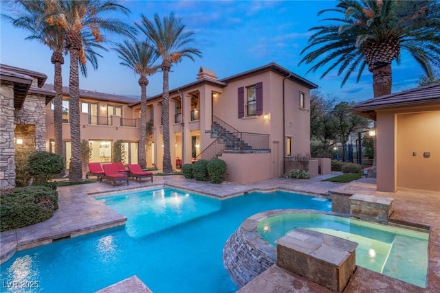 pool at dusk featuring a patio and an in ground hot tub