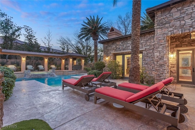 pool at dusk with a patio and pool water feature