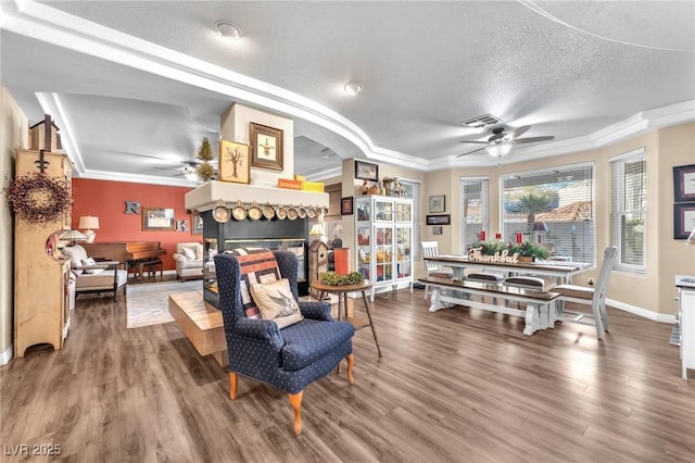 living area featuring a stone fireplace, hardwood / wood-style floors, a textured ceiling, and ceiling fan