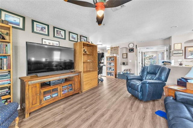 living room with hardwood / wood-style flooring, ceiling fan, and a textured ceiling