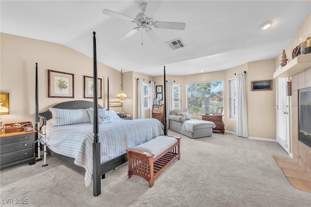 carpeted bedroom with lofted ceiling, a tile fireplace, and ceiling fan