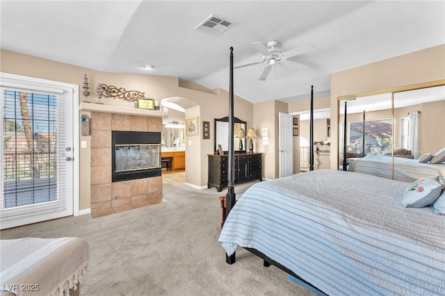 bedroom with a tile fireplace, ceiling fan, vaulted ceiling, light carpet, and access to outside