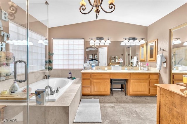 bathroom with vanity, lofted ceiling, tiled bath, and a chandelier