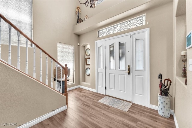 foyer entrance with hardwood / wood-style flooring and a towering ceiling