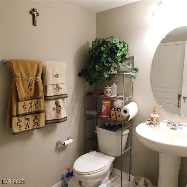 half bath featuring baseboards, a sink, and toilet