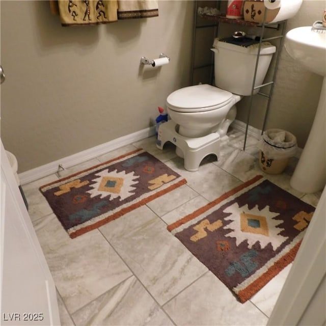 half bath with tile patterned floors, toilet, and baseboards