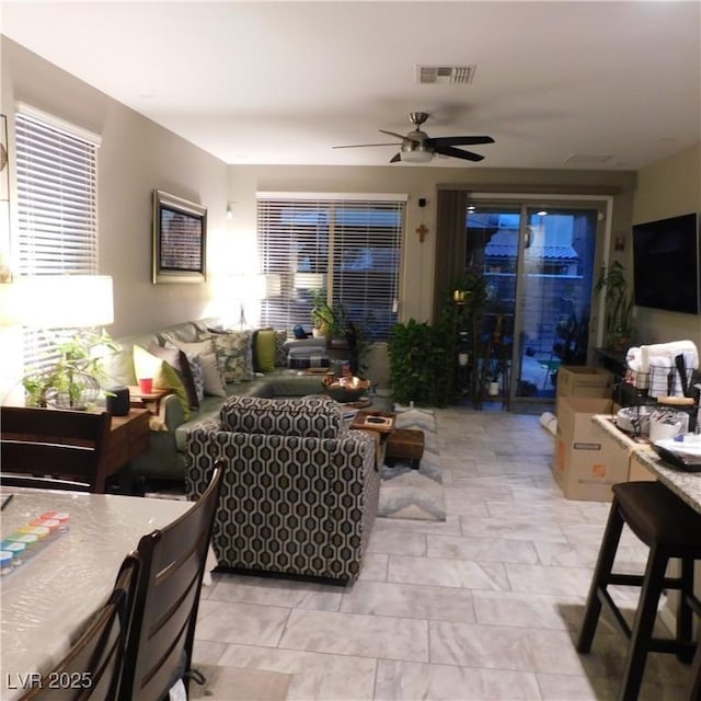 living area featuring ceiling fan and visible vents