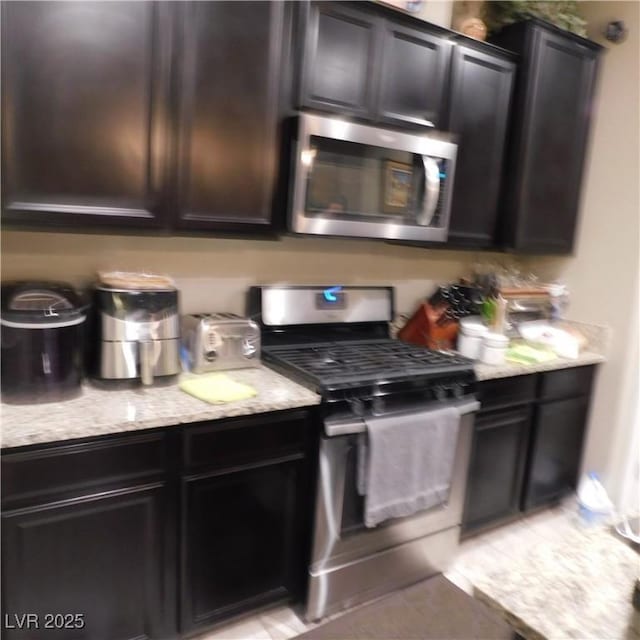 kitchen featuring appliances with stainless steel finishes and light stone counters