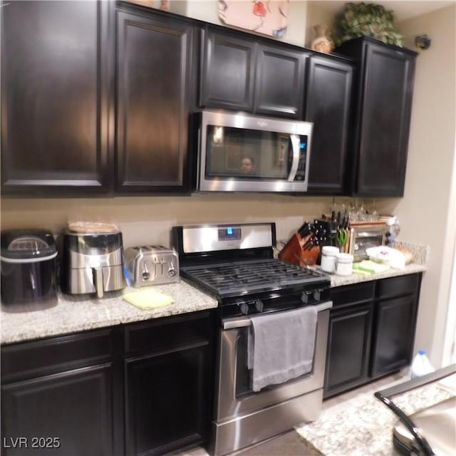 kitchen with light stone countertops and appliances with stainless steel finishes