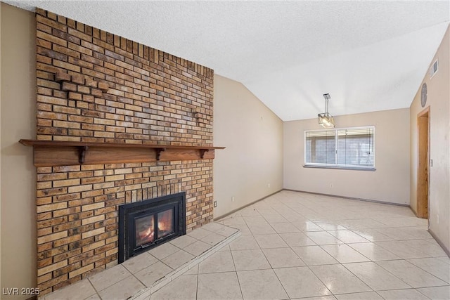 unfurnished living room with lofted ceiling, a brick fireplace, light tile patterned floors, and a textured ceiling