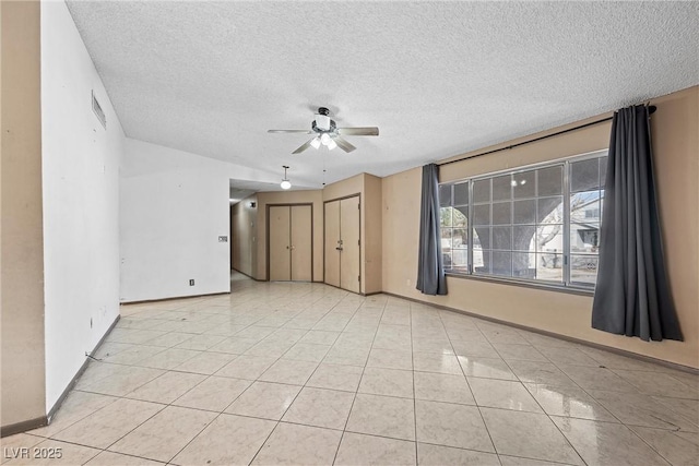 tiled spare room with a textured ceiling and ceiling fan