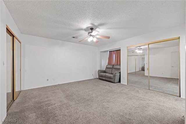 unfurnished bedroom with ceiling fan, a textured ceiling, carpet floors, and multiple closets