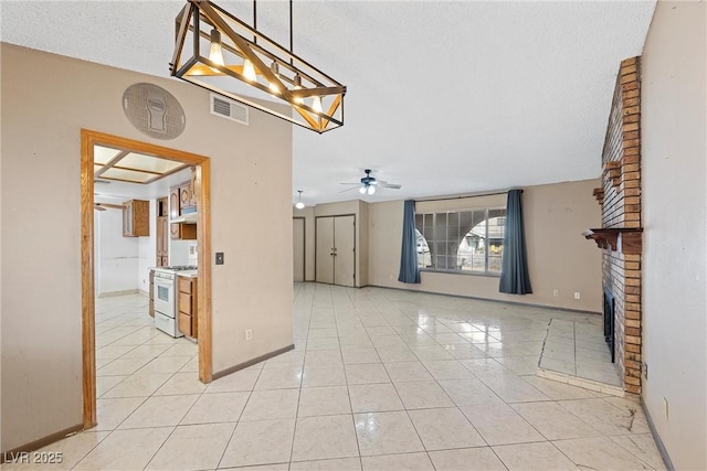 interior space featuring light tile patterned flooring, a brick fireplace, ceiling fan, and a textured ceiling