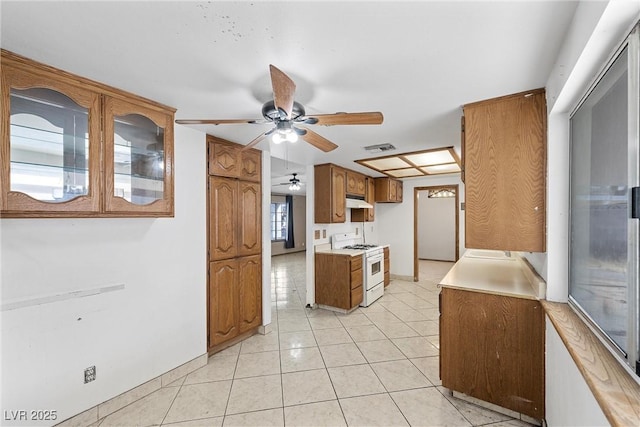 kitchen with light tile patterned flooring, white gas range, and ceiling fan