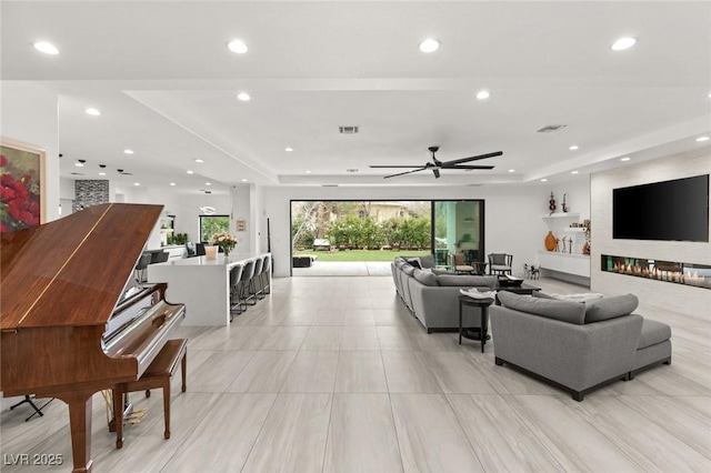 living room featuring a raised ceiling and ceiling fan