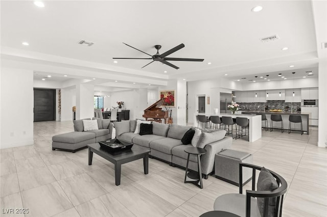 living room with a tray ceiling and ceiling fan